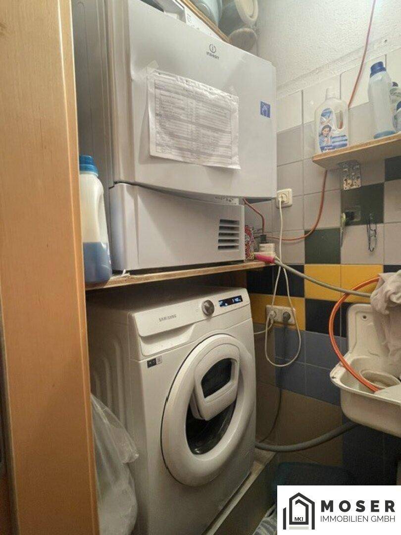 Funktionaler Hauswirtschaftsraum mit Waschmaschine, Gefrierschrank und kleinem Waschbecken.