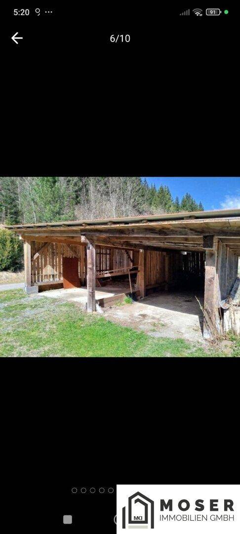 Offener Holzschuppen oder Carport-Struktur auf dem Grundstück.