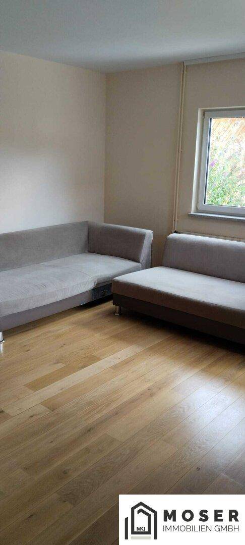 Helles Wohnzimmer mit zwei grauen Sofas und hellem Holzparkettboden.