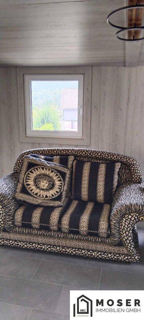 Wohnbereich mit auffällig gemustertem Sofa und modernem Fliesenboden.