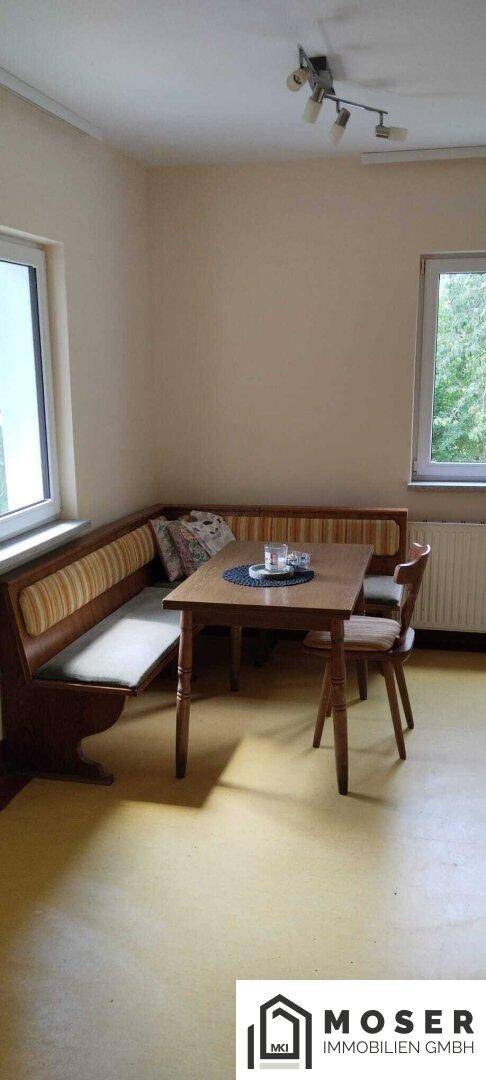Gemütlicher Essbereich mit Eckbank, Holztisch und gelbem Linoleumboden.