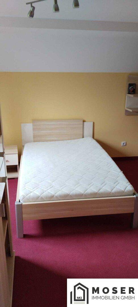 Schlafzimmer mit Doppelbett und rotem Teppichboden.