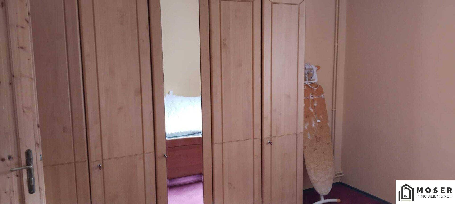 Schlafzimmer mit großen Holzschränken und Spiegeltüren.