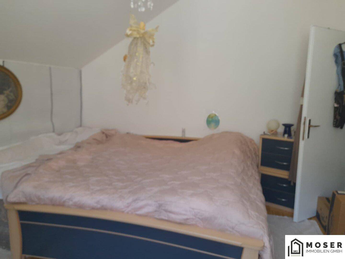Schlafzimmer mit großem Bett, Dachschräge und einfacher Dekoration, hell und einladend.