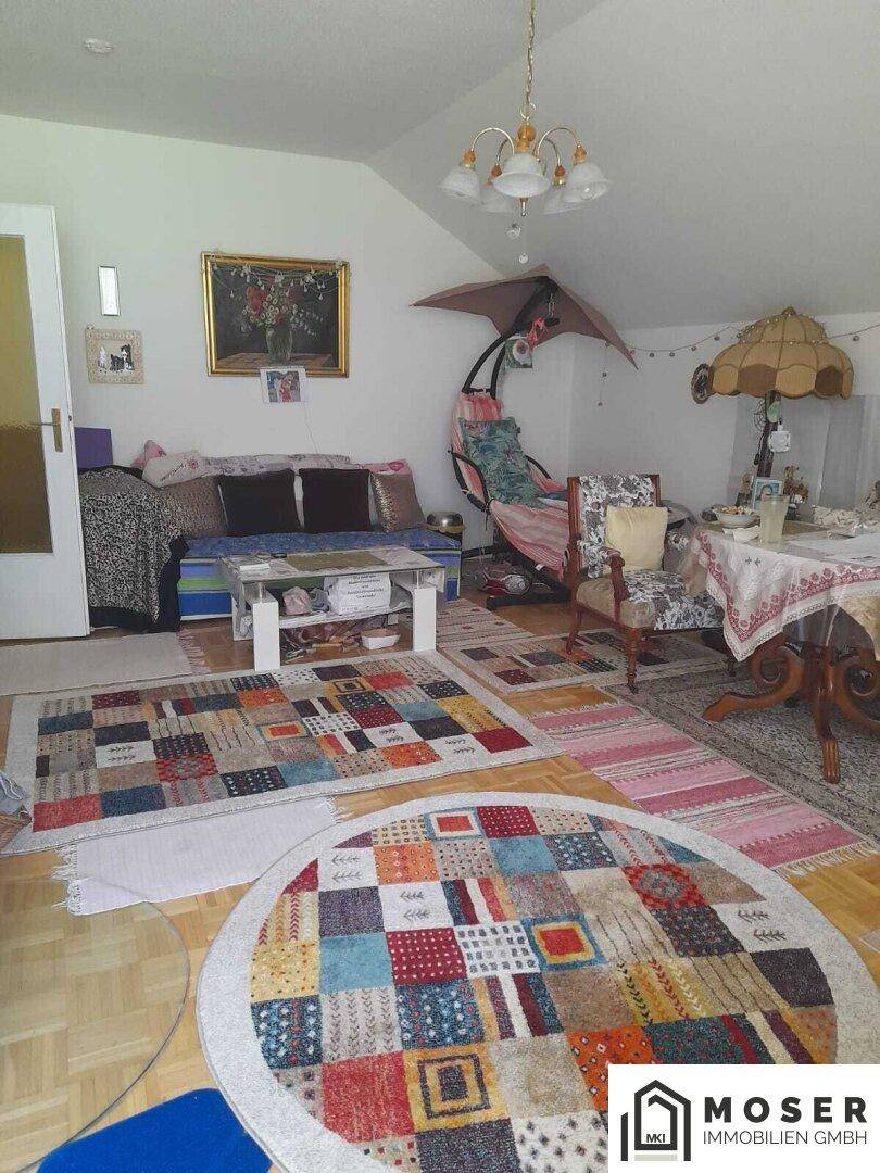 Geräumiges Wohnzimmer mit Holzboden, bunten Teppichen und verschiedenen Sitzgelegenheiten in offener Gestaltung.