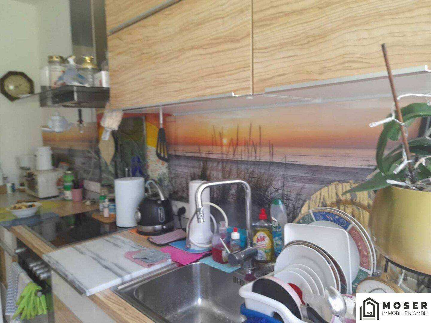 Moderne Küche mit Holzelementen, Spüle und einer dekorativen Rückwand mit Sonnenuntergangsmotiv.