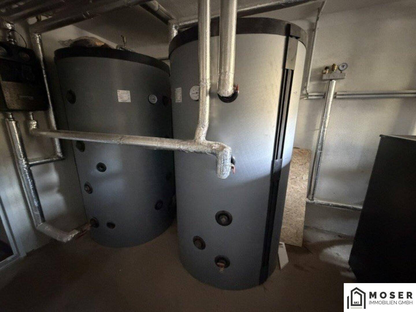Zwei große Wassertanks und umfangreiche Rohrleitungen im Heizungsraum, für Warmwasserversorgung.