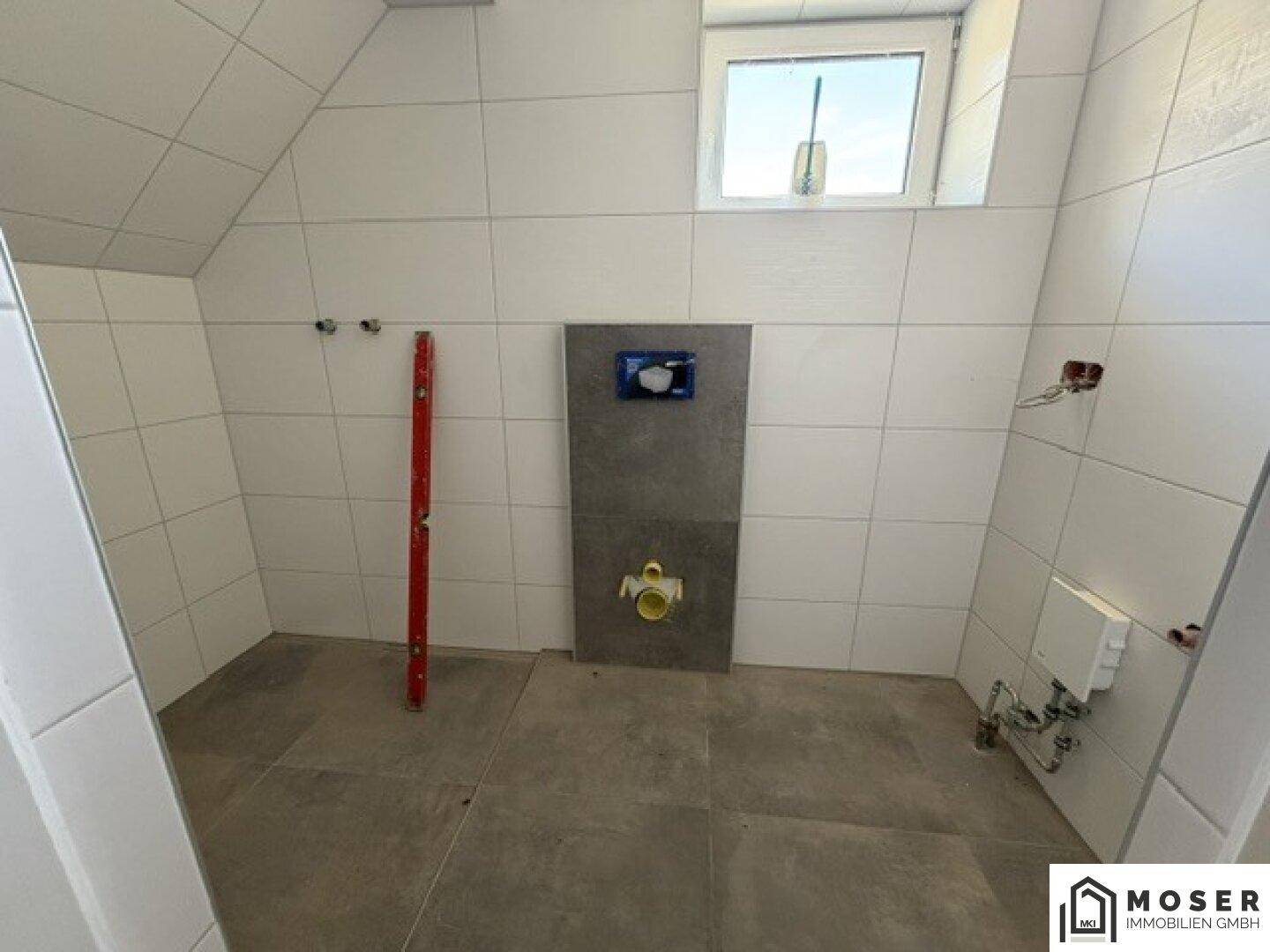 Unfertiges Badezimmer mit weißen Fliesen, bereit für die Installation der Sanitärobjekte.