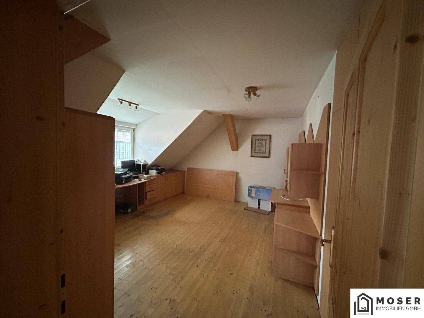 Schlafzimmer im Dachgeschoss mit Holzdielenboden, Dachschräge und einfacher Einrichtung.