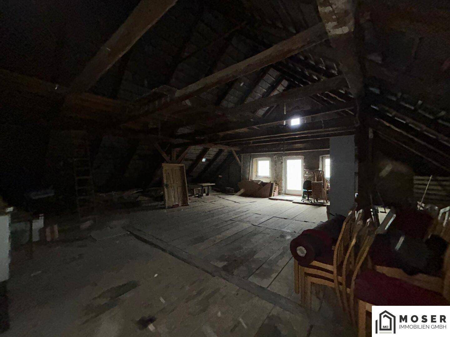 Großer, ungenutzter Dachboden mit sichtbaren Holzbalken und Holzdielenboden.