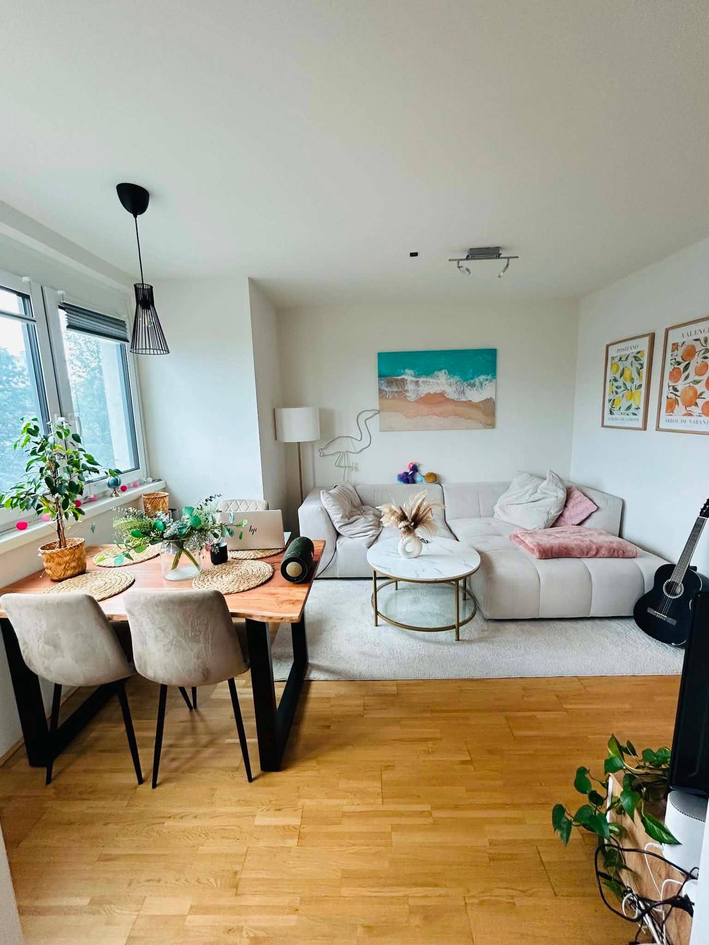 Offener Wohn- und Essbereich mit hellem Sofa, Holztisch und großen Fenstern für viel Licht.