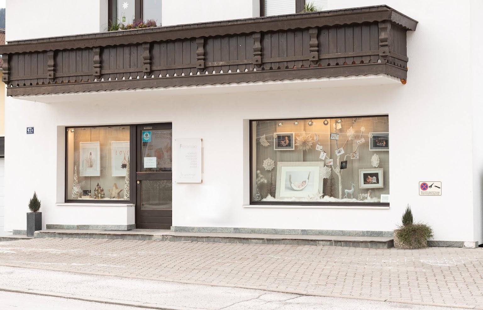 Nahaufnahme der Ladenfront mit großen Schaufenstern und traditionellem Holzbalkon darüber.