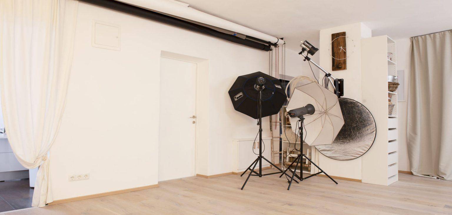 Fotostudio mit professioneller Beleuchtungsausrüstung und einer weißen Tür im Hintergrund.