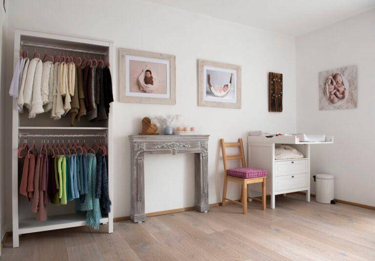 Heller Raum mit Kleiderschrank, Wickeltisch und dekorativem Kamin, eingerichtet für Babyfotografie.