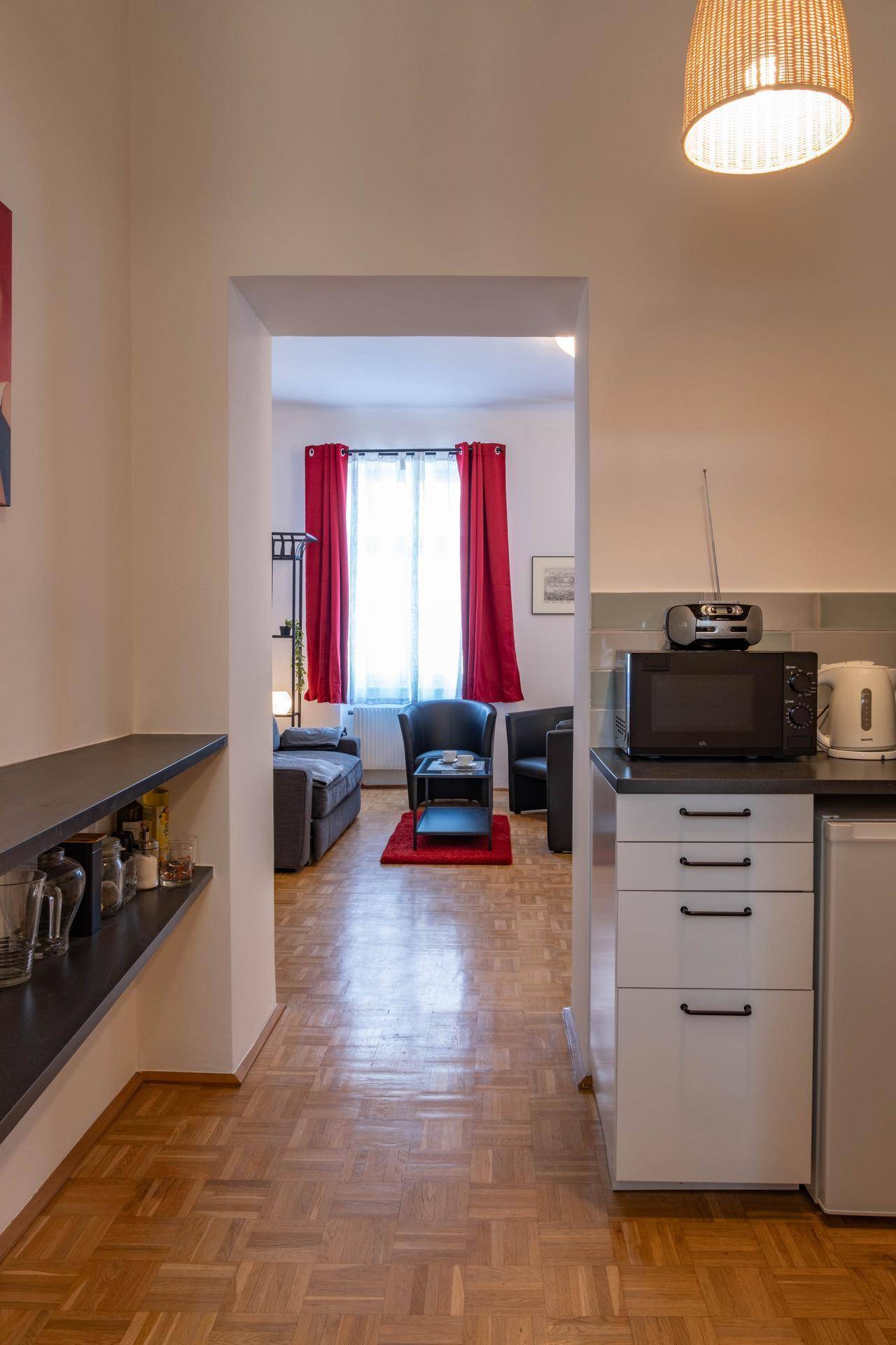 Flur mit kleiner Küchenzeile und Blick in das angrenzende, hell beleuchtete Wohnzimmer.