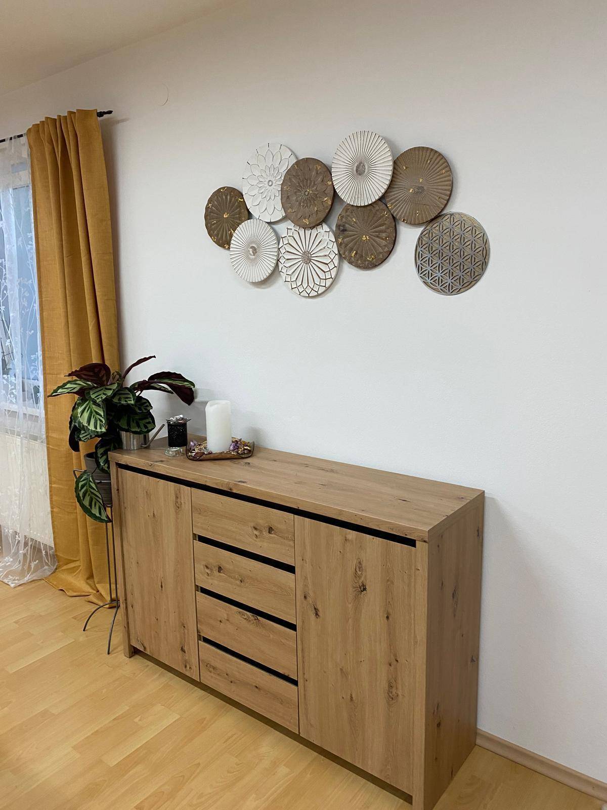 Moderner Holzschrank mit dekorativen Wandelementen und einer Pflanze, der den hellen Raum mit Holzboden ergänzt.