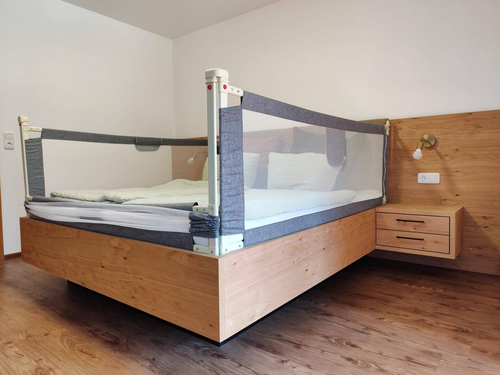 Schlafzimmer mit Holzbett, schwebenden Nachttischen und Holzboden.