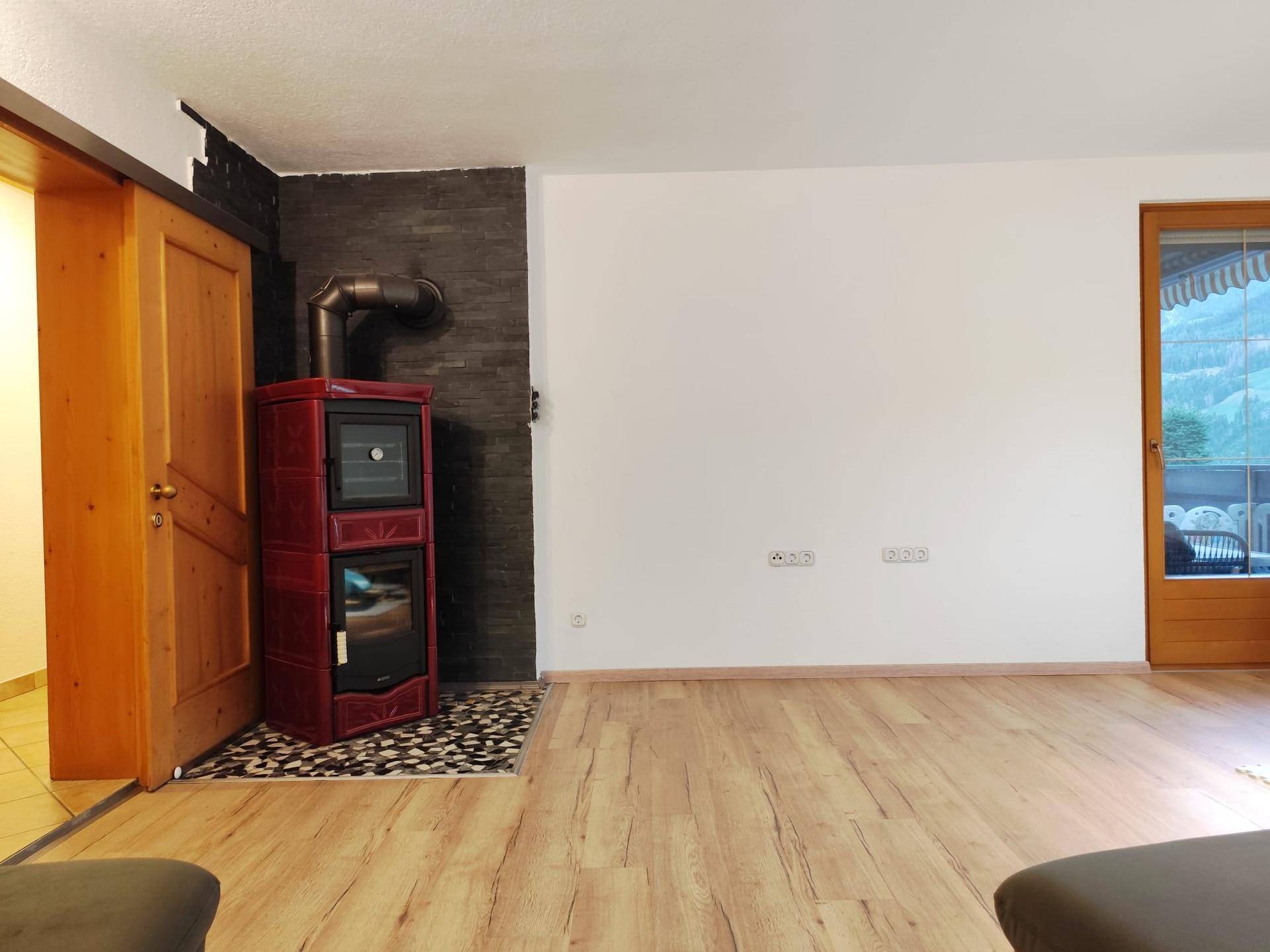 Wohnzimmer mit Holzboden und einem modernen Kaminofen als gemütliches Heizelement.