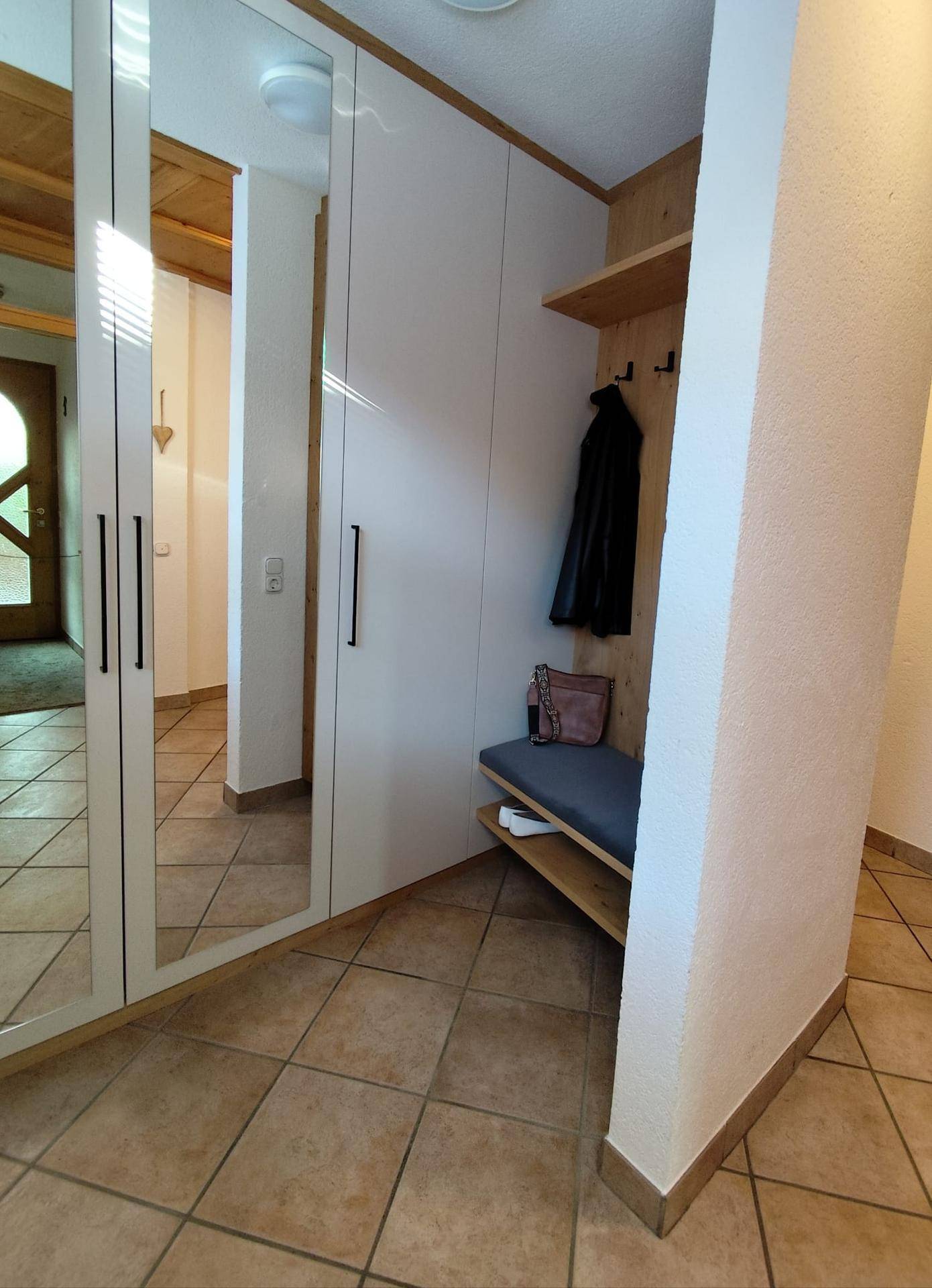 Heller Flur mit Spiegelschränken, Holzelementen und traditionellem Fliesenboden.