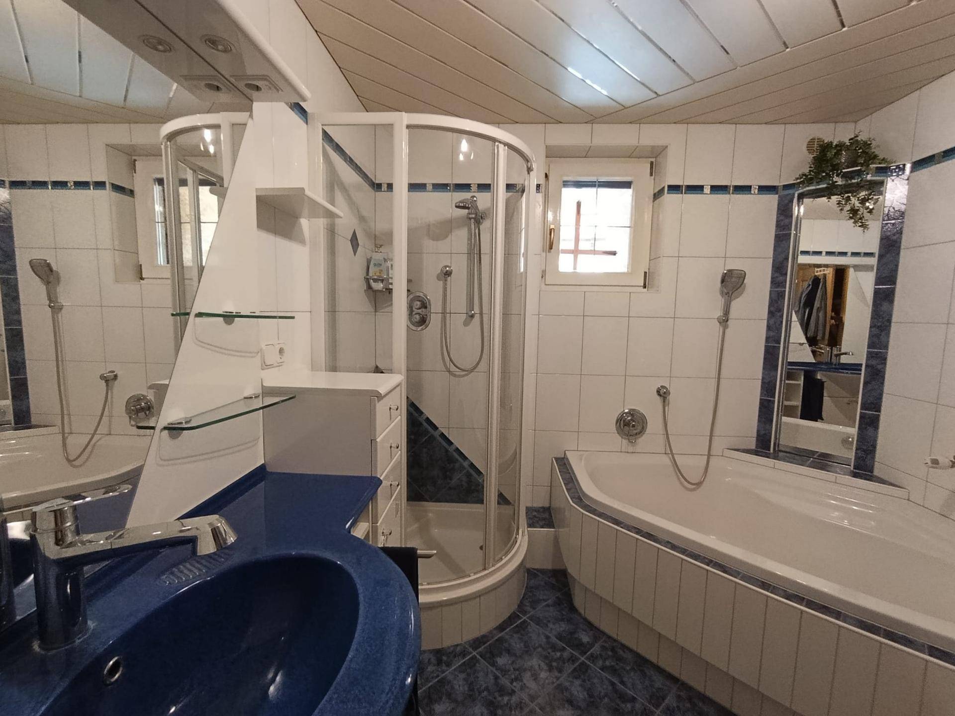 Badezimmer mit blauen Akzenten, Dusche, Badewanne und zwei Waschbecken.