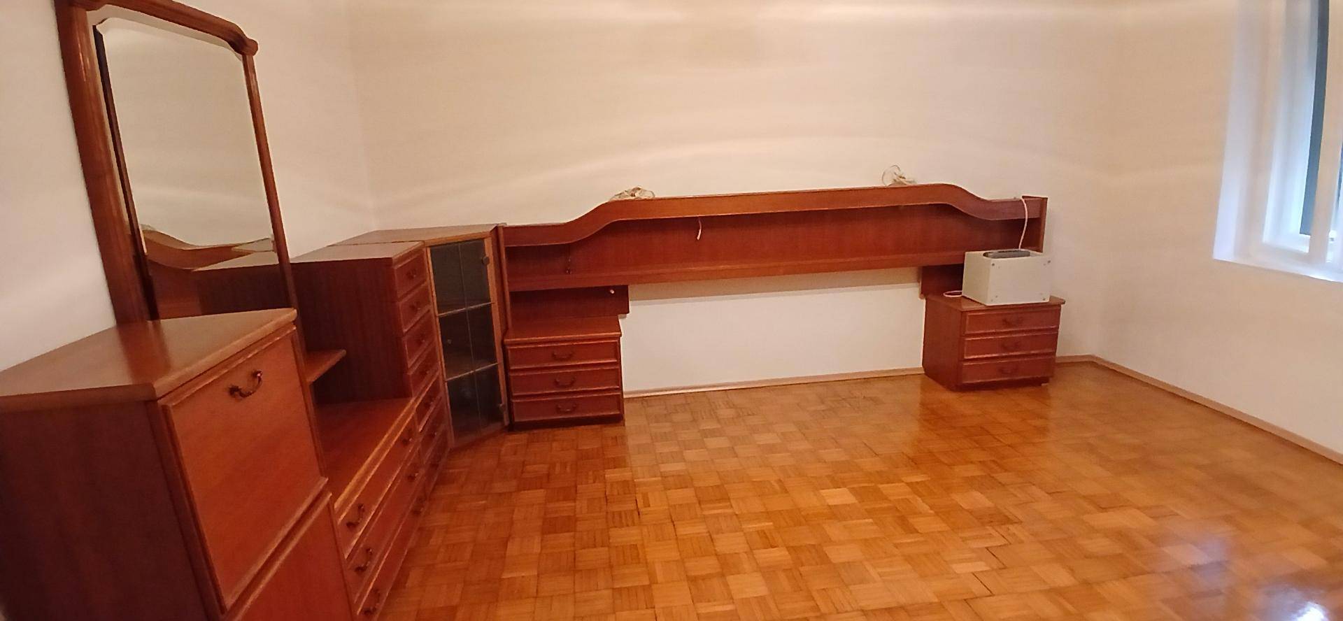 Geräumiges Schlafzimmer mit Parkettboden und traditionellen Holzmöbeln, bereit zur Einrichtung.