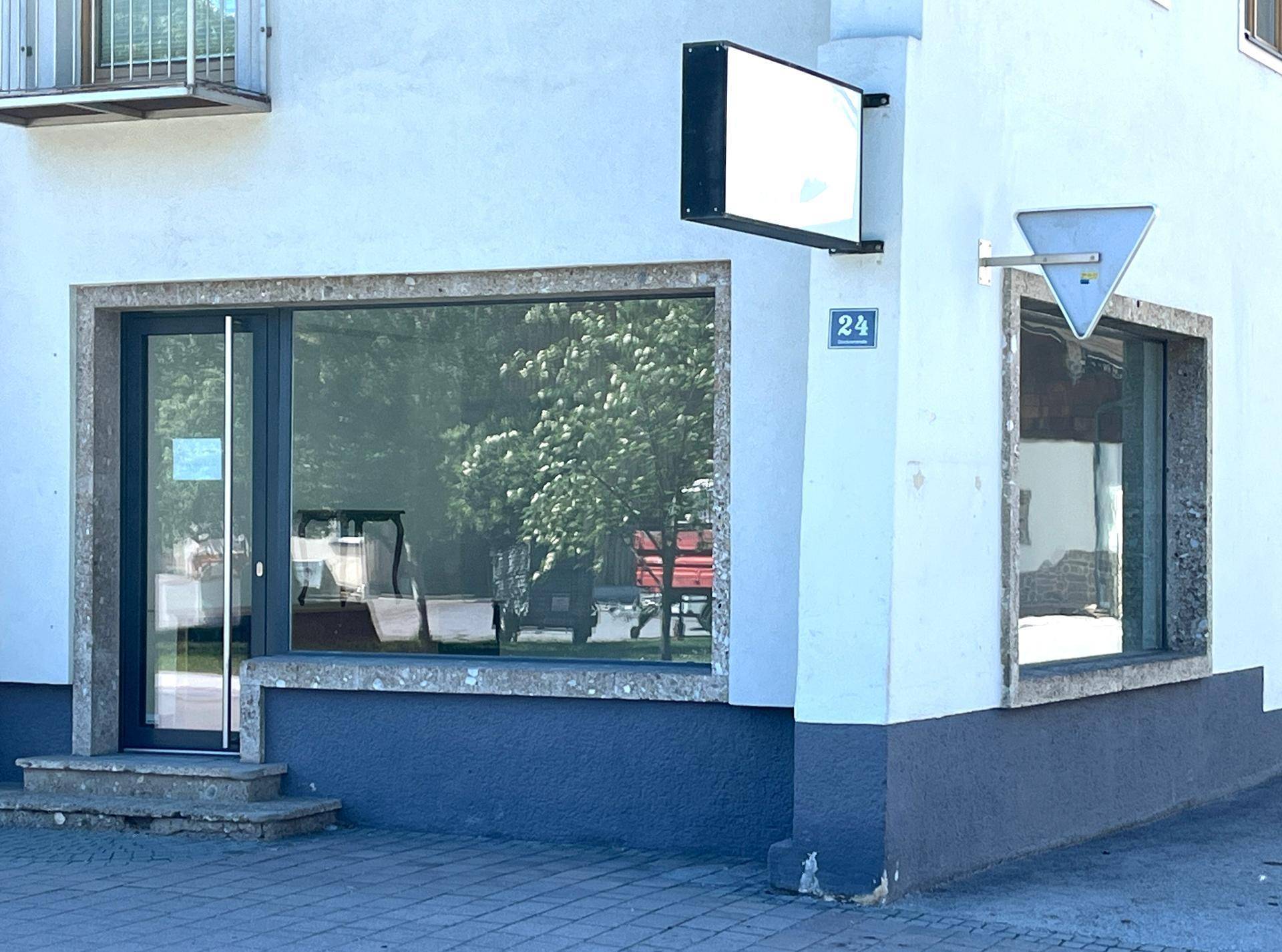Außenansicht eines modernen Geschäftsgebäudes mit großen Schaufenstern und weißer Fassade.