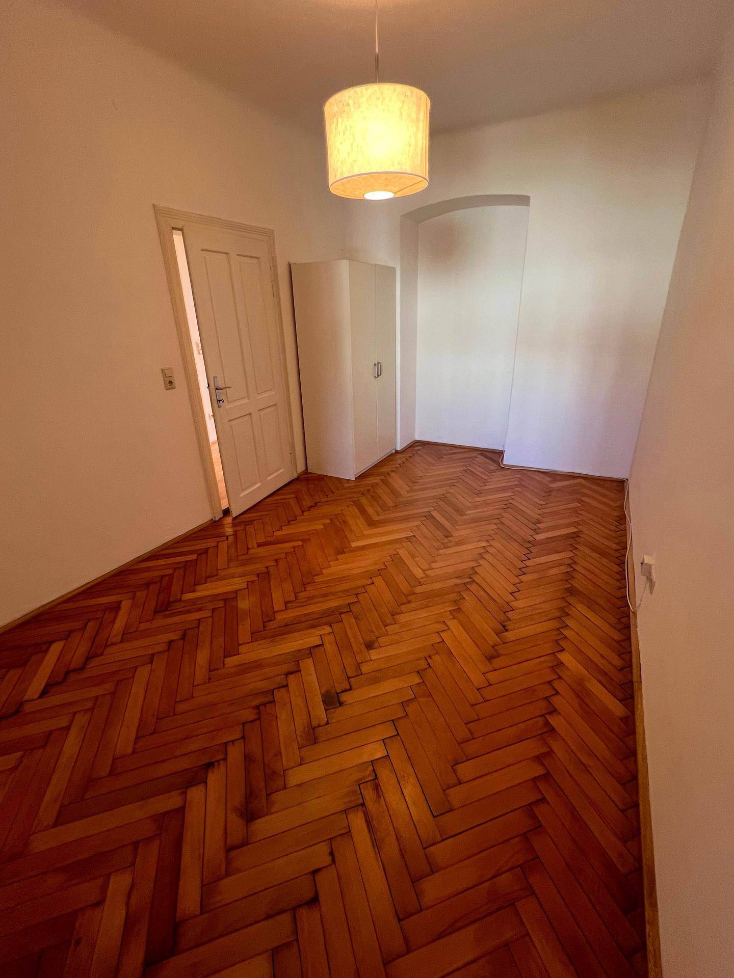 Zimmer mit Fischgrätparkett und einem Einbauschrank, bereit zur individuellen Gestaltung.