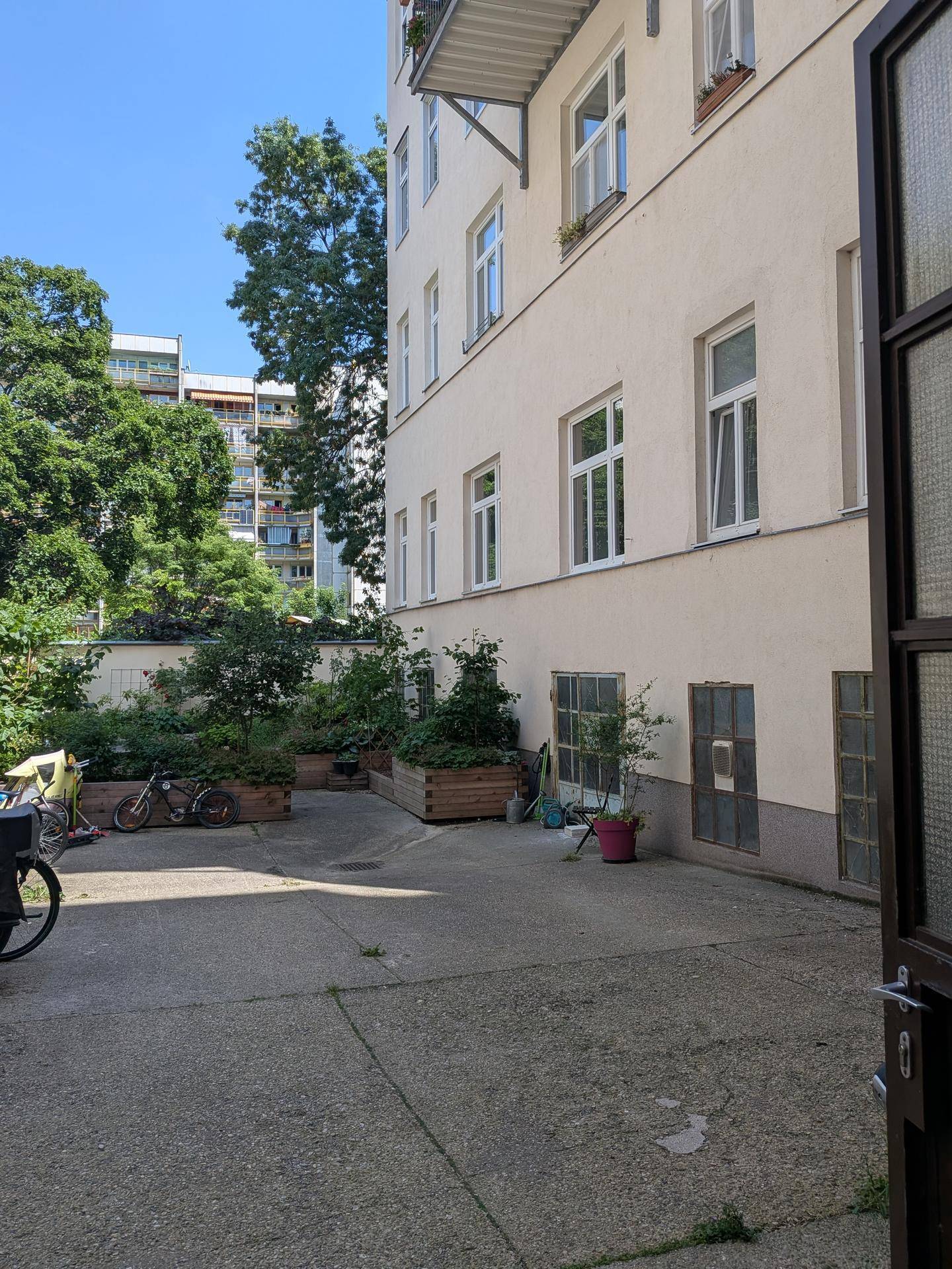 Grüner Innenhof eines Mehrfamilienhauses mit Fahrradstellplätzen und Bepflanzung.
