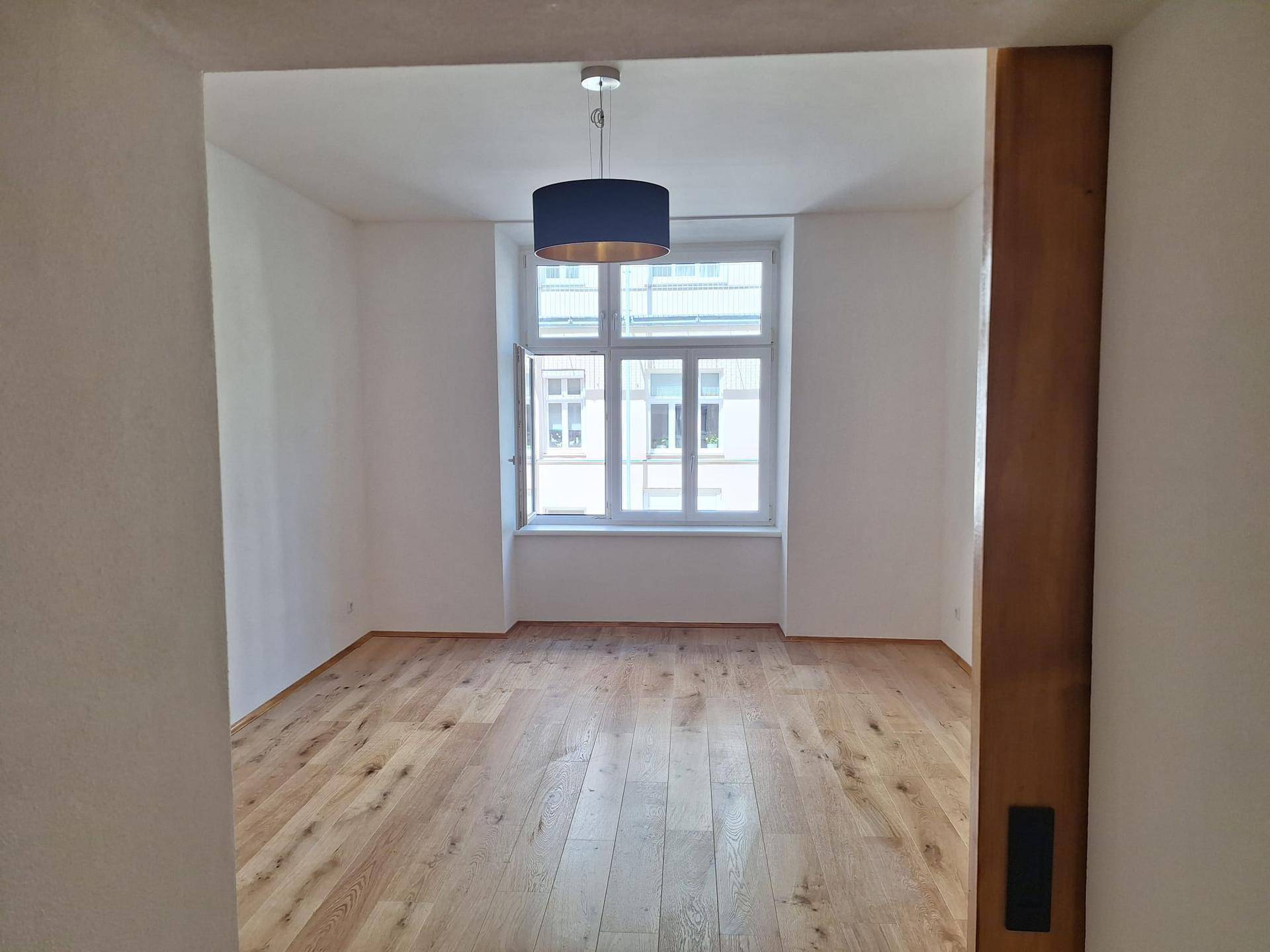 Helles Wohnzimmer mit neuem Eichenparkettboden und großen Fenstern.