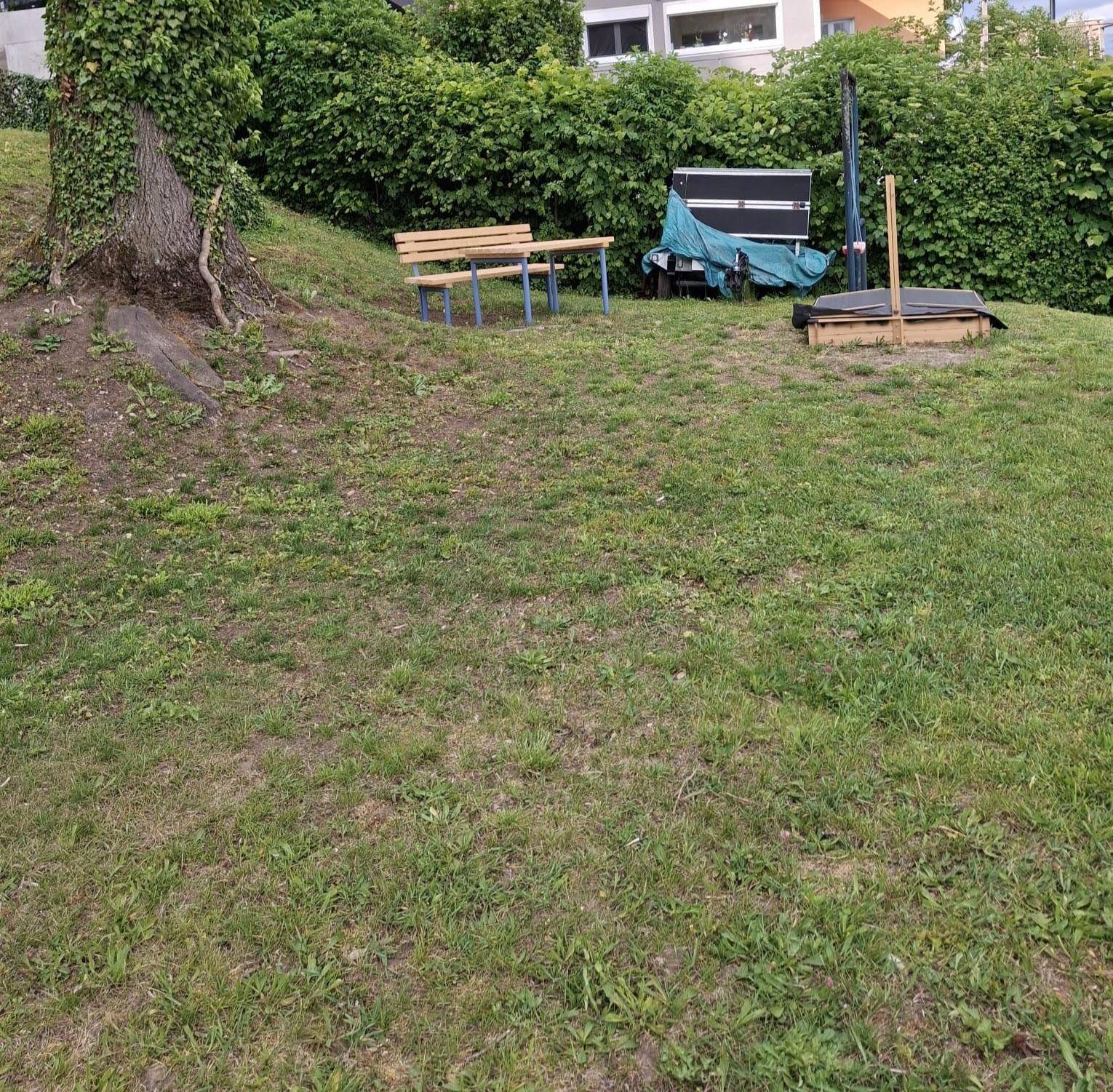 Grüne Gartenfläche mit Sitzbank und Tisch, ideal für Erholung im Freien.