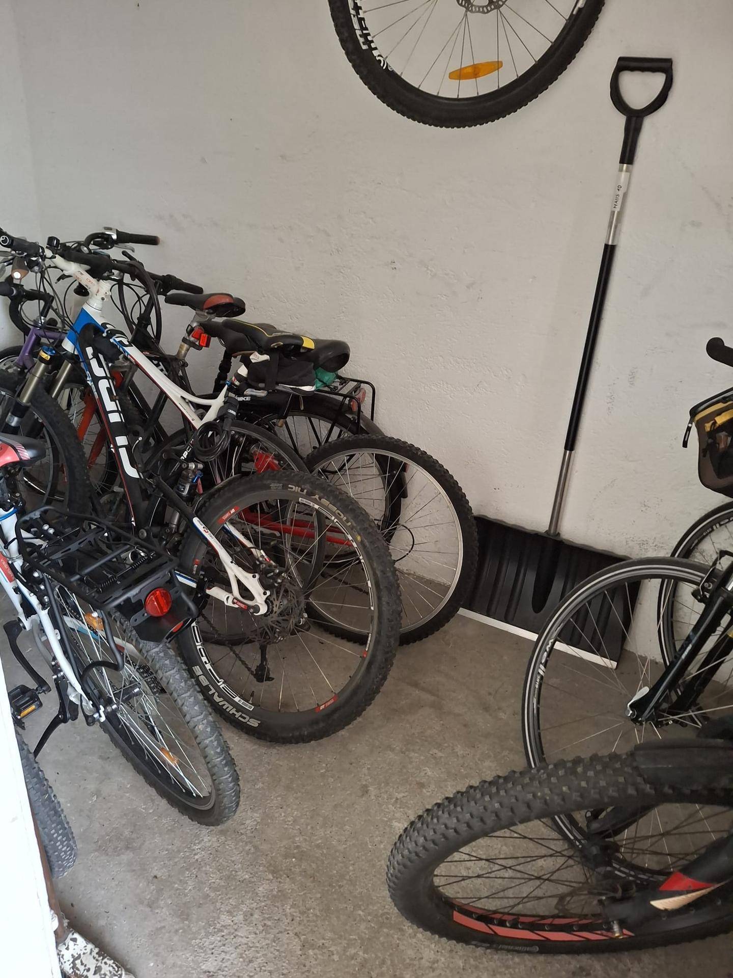Gemeinschaftlicher Fahrradraum mit mehreren abgestellten Fahrrädern und einer Schaufel.