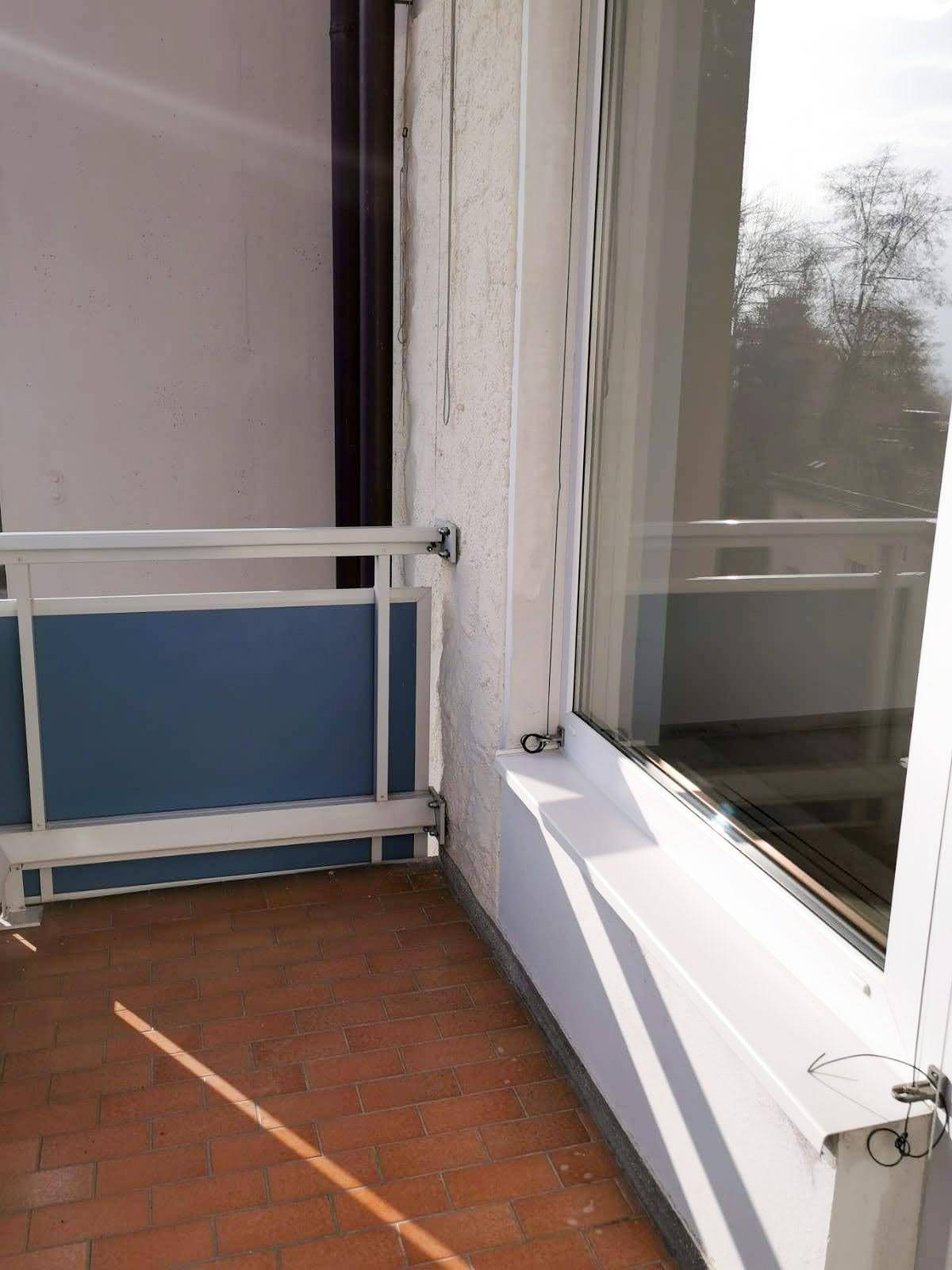 Kleiner Balkon mit Terrakotta-Fliesen und blauem Geländer, ideal für entspannte Stunden.