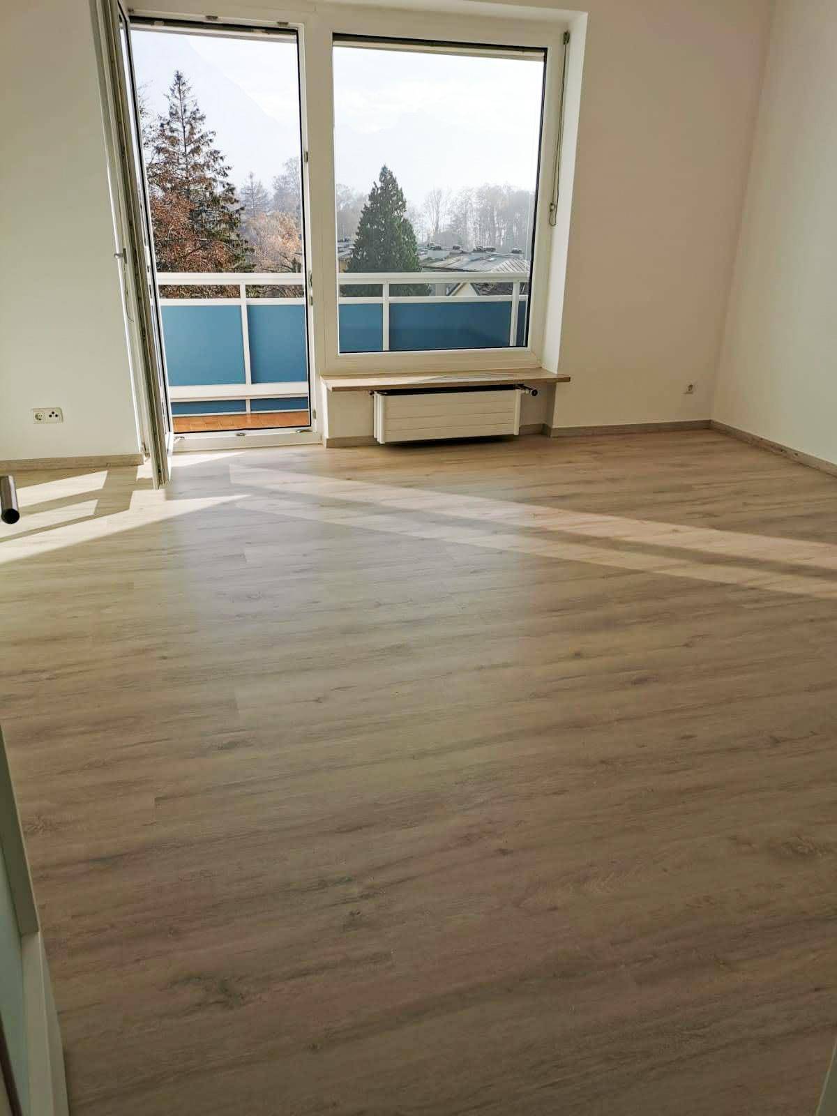 Heller, leerer Raum mit Laminatboden und Zugang zu einem kleinen Balkon, ideal für Wohnzwecke.