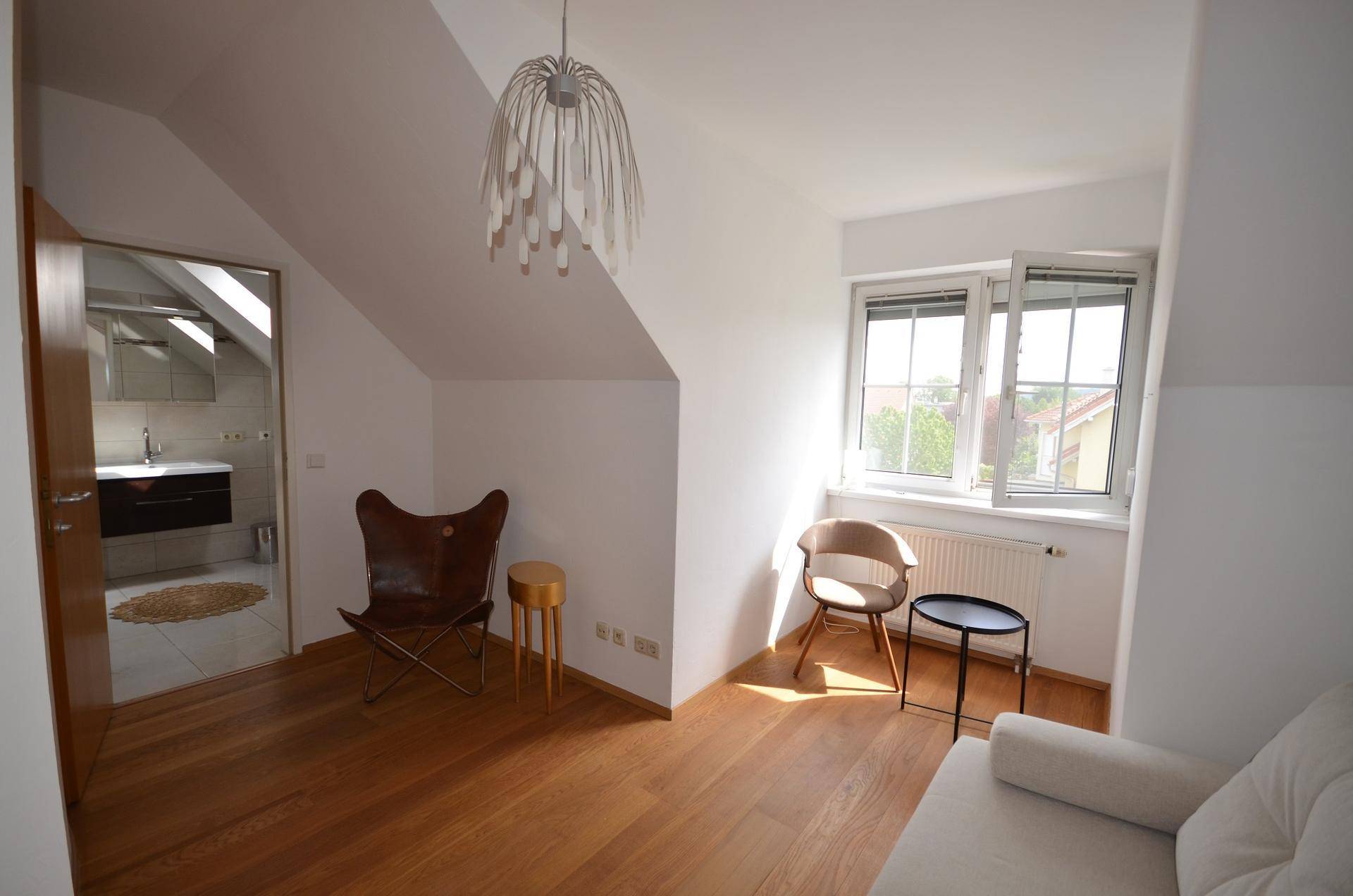 Helles Schlafzimmer mit Holzboden, Dachschräge und modernem Mobiliar.