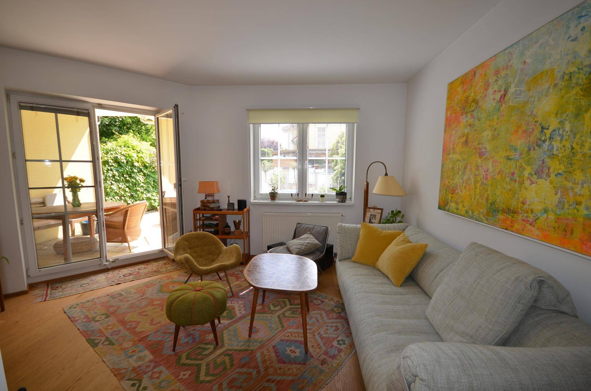Gemütliches Wohnzimmer mit farbenfrohem Teppich und direktem Zugang zur sonnigen Terrasse.