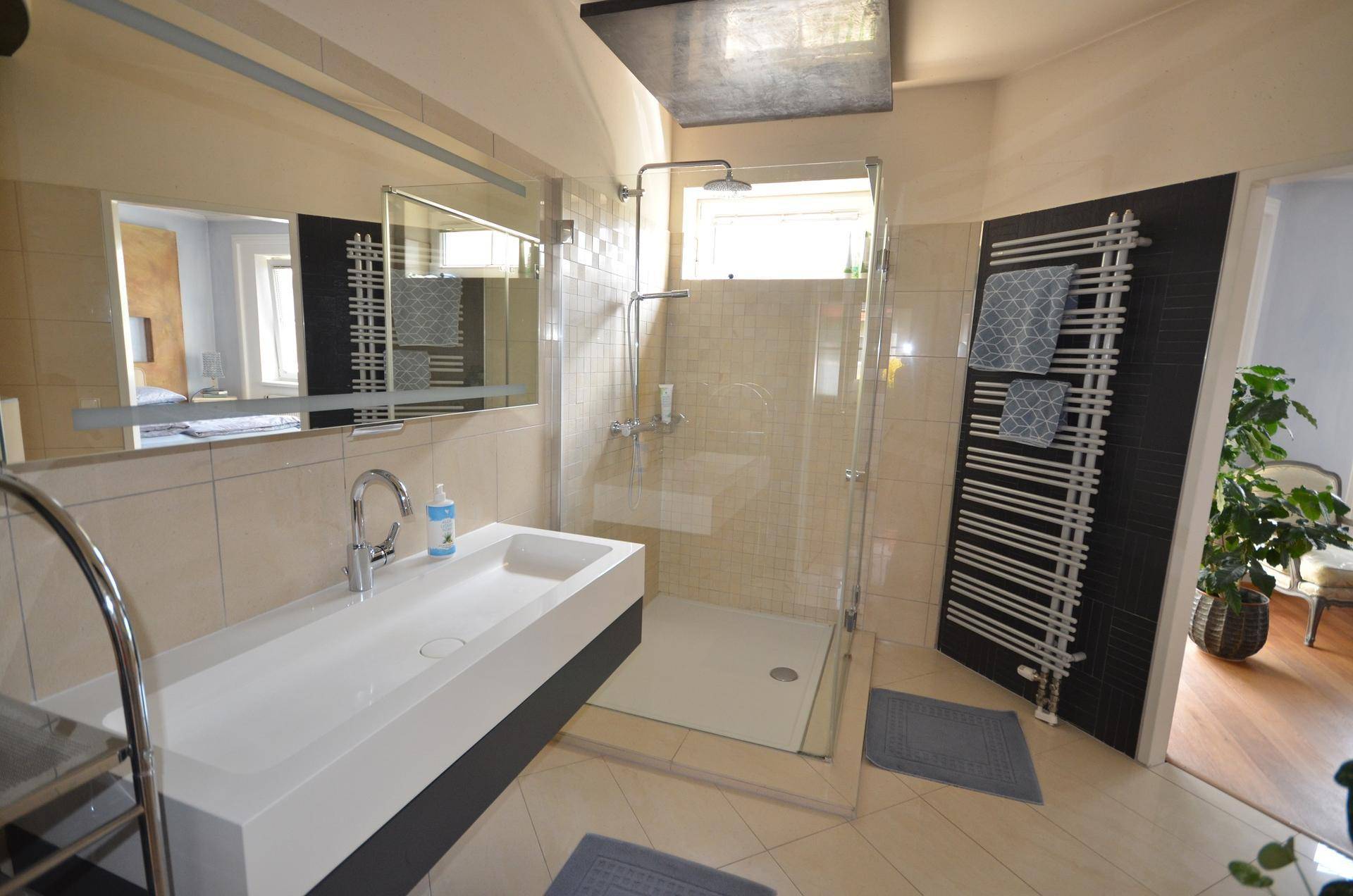 Modernes Badezimmer mit begehbarer Dusche, stilvollem Waschbecken und Handtuchheizkörper.