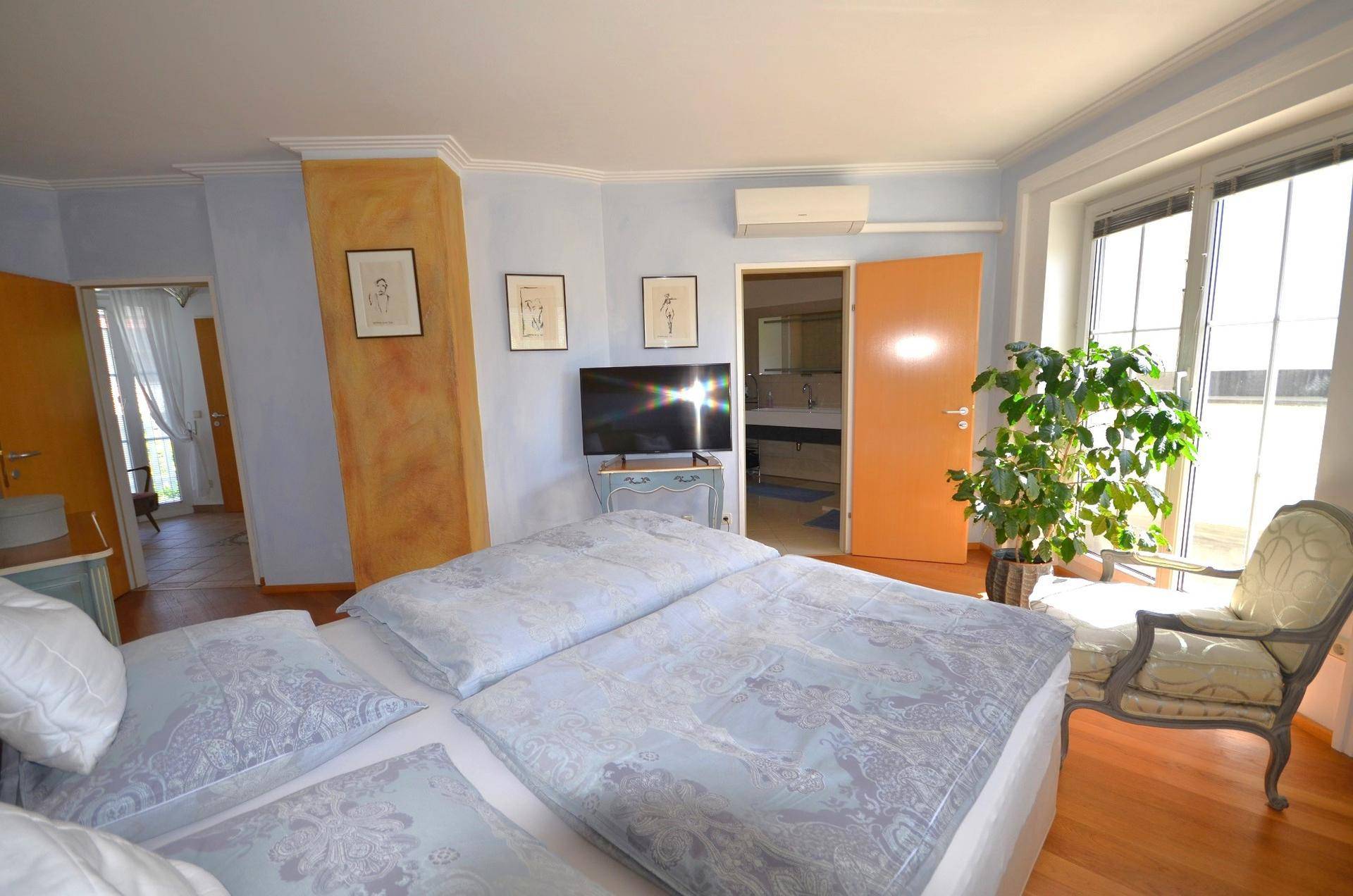 Geräumiges Schlafzimmer mit Holzboden, Doppelbett und direktem Zugang zum Badezimmer.