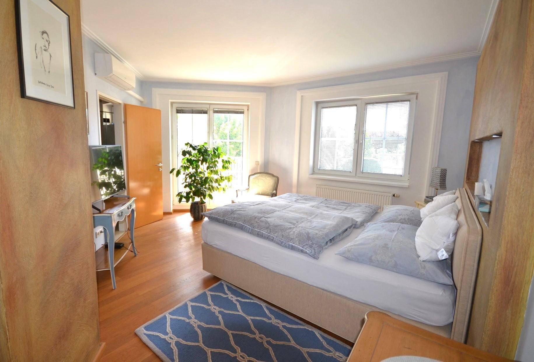 Helles Schlafzimmer mit Doppelbett, Holzboden, Klimaanlage und Zugang zum Balkon.