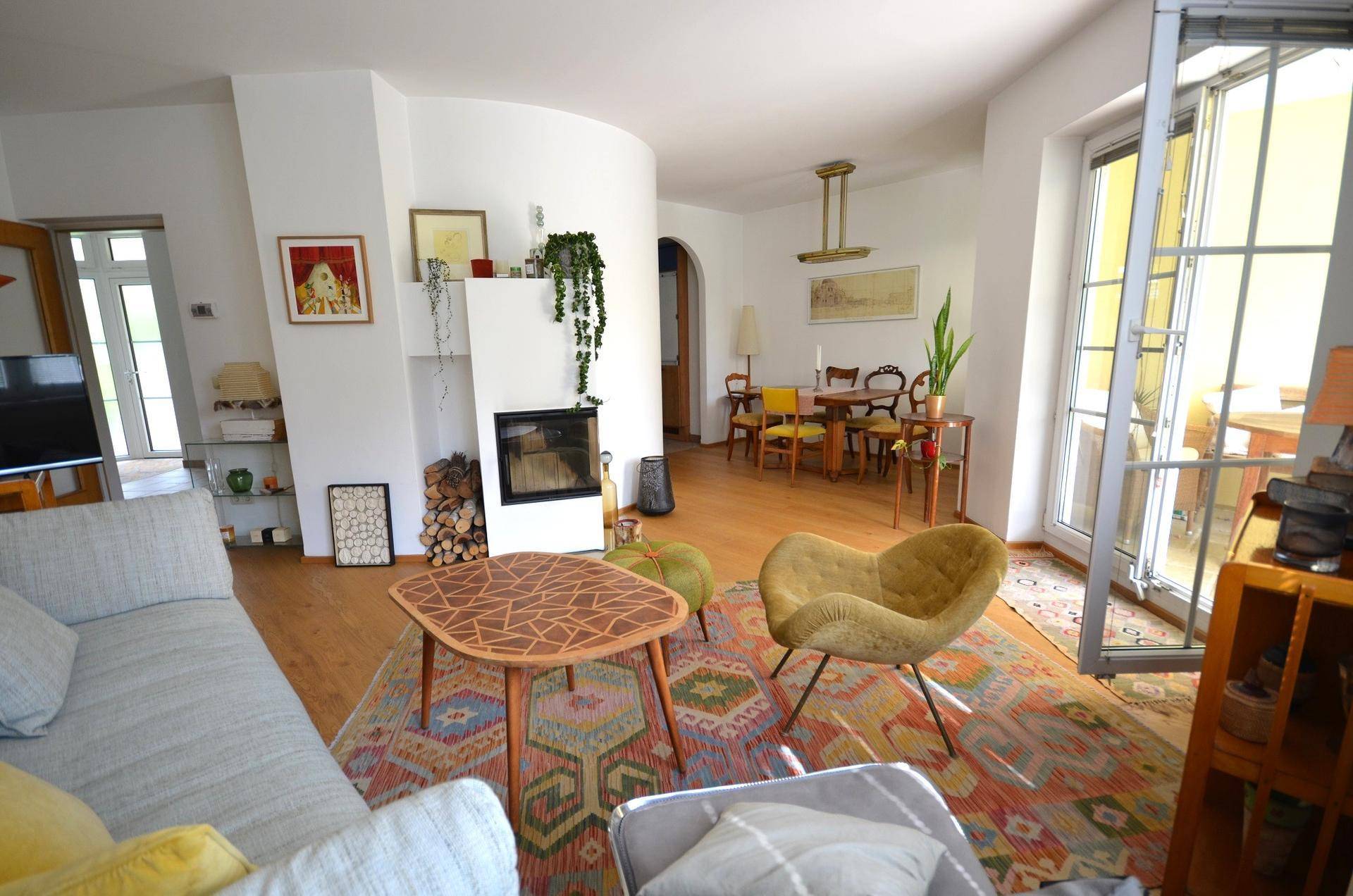 Offener Wohn-Essbereich mit modernem Kamin, Holzboden und Zugang zur Terrasse.