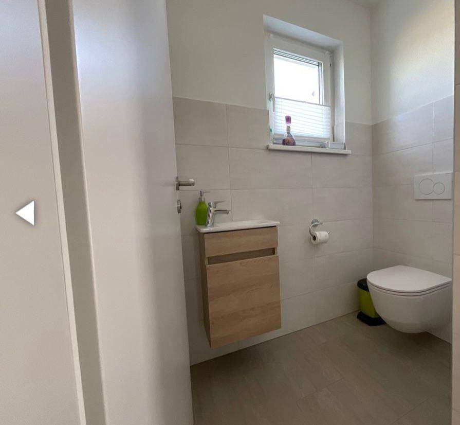 Modernes Gäste-WC mit wandhängendem WC, kleinem Waschbecken und Fenster.