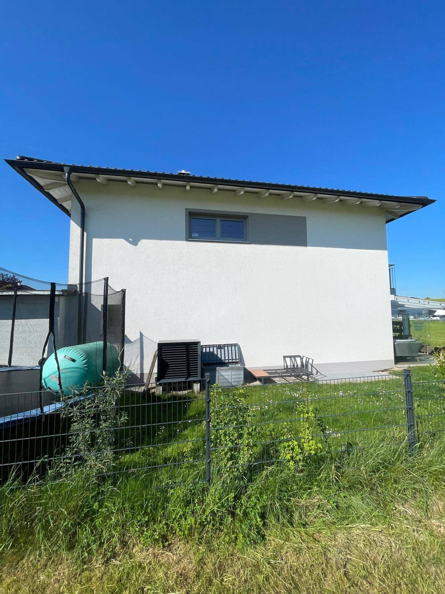 Seitenansicht des Hauses mit Gartenbereich und Trampolin im Hintergrund.