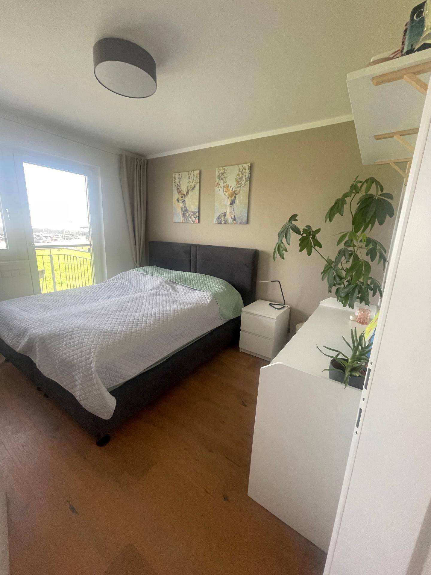 Gemütliches Schlafzimmer mit Doppelbett, Holzboden und Blick ins Grüne.