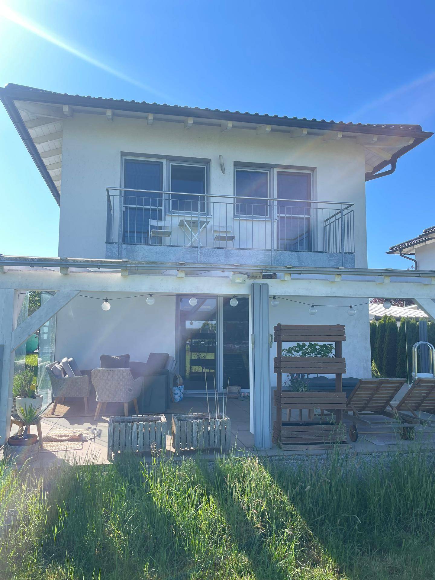 Rückseite des Hauses mit großzügiger Terrasse, Balkon und Blick ins Grüne.