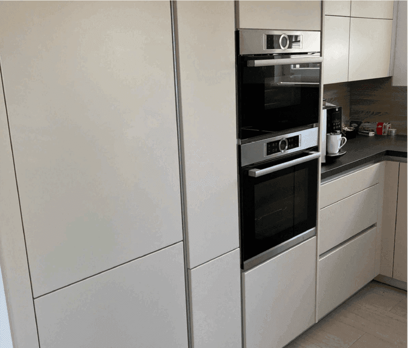 Integrierte Küchengeräte mit Backofen, Mikrowelle und Kaffeemaschine in modernen Schränken.