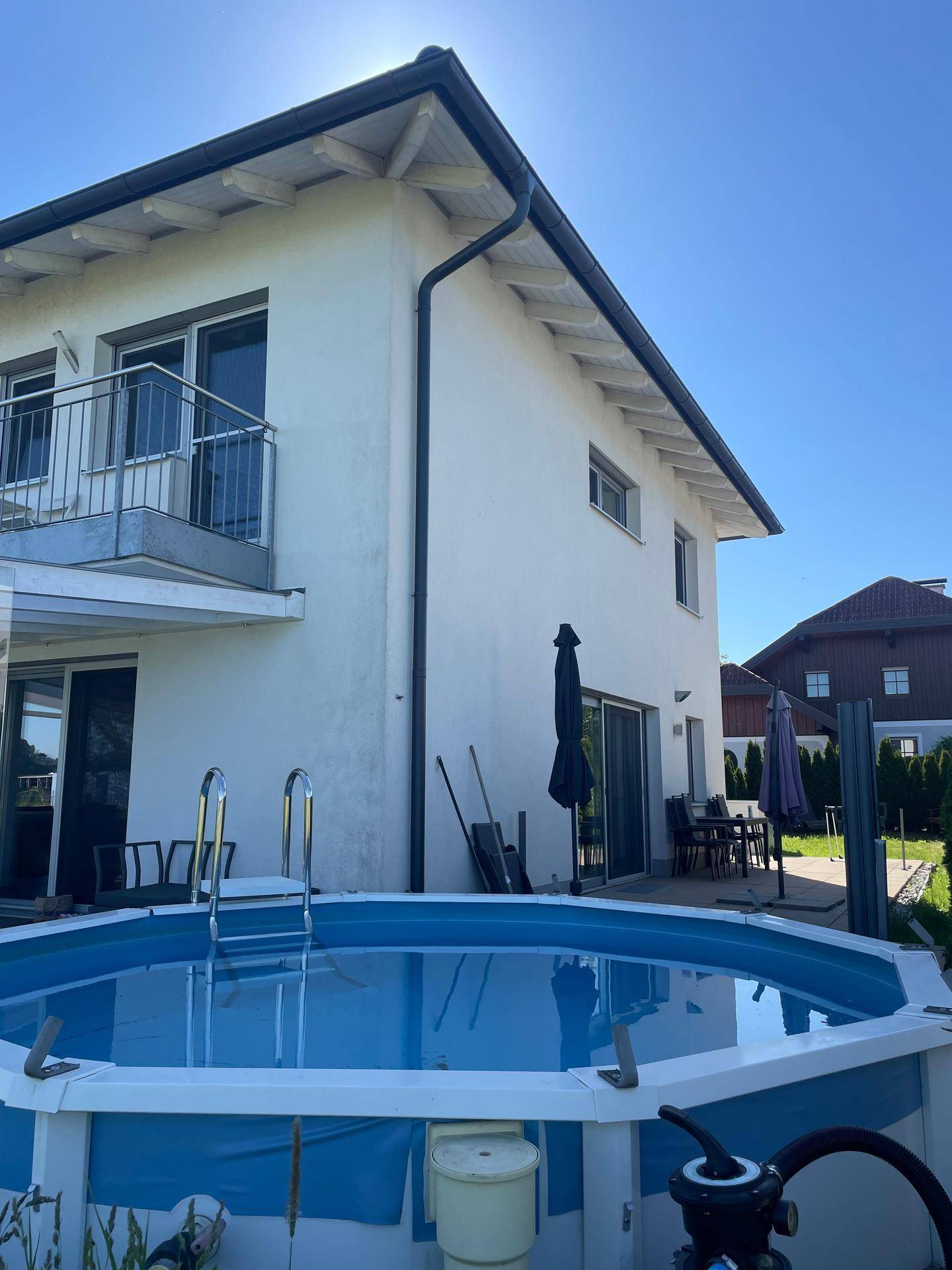 Terrasse mit Zugang zum Aufstellpool und Blick auf die Hausfassade.