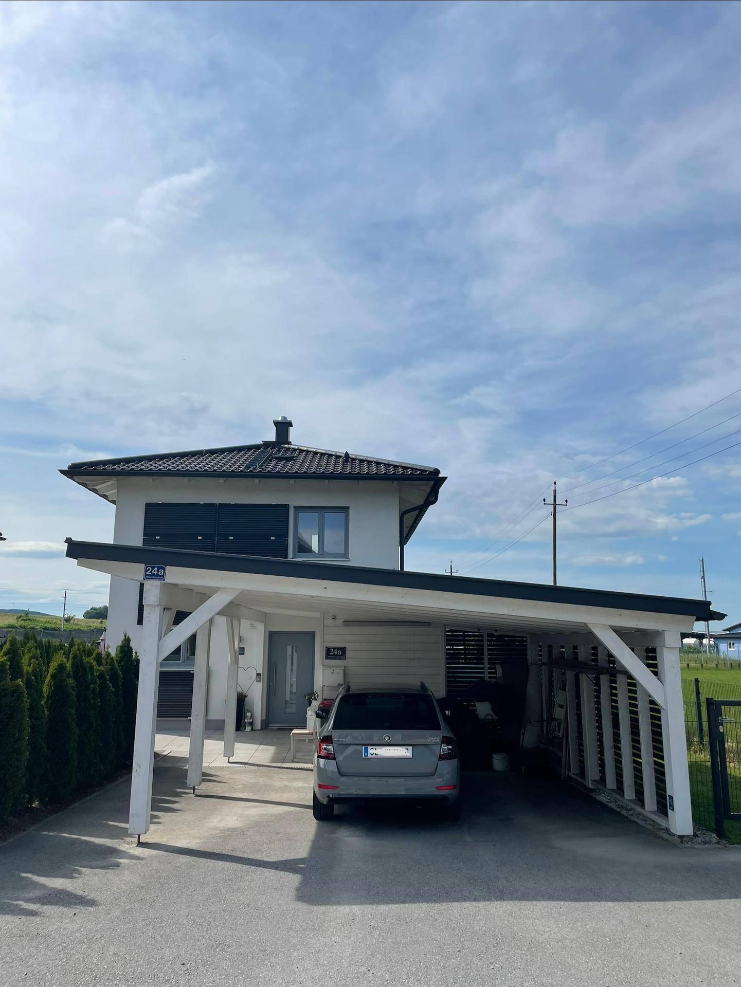 Vorderansicht eines modernen Einfamilienhauses mit Carport und gepflegter Auffahrt.