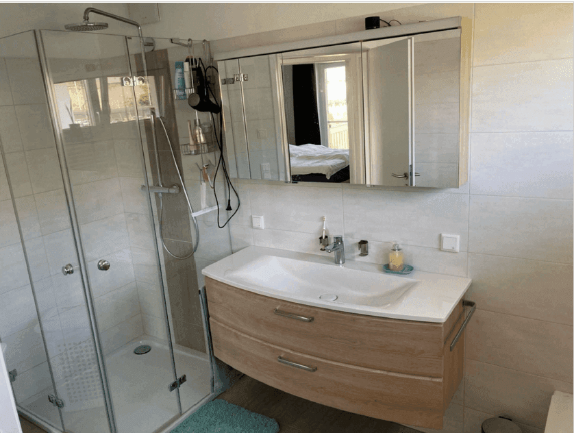 Modernes Badezimmer mit Duschkabine, Waschbecken und Spiegelschrank.