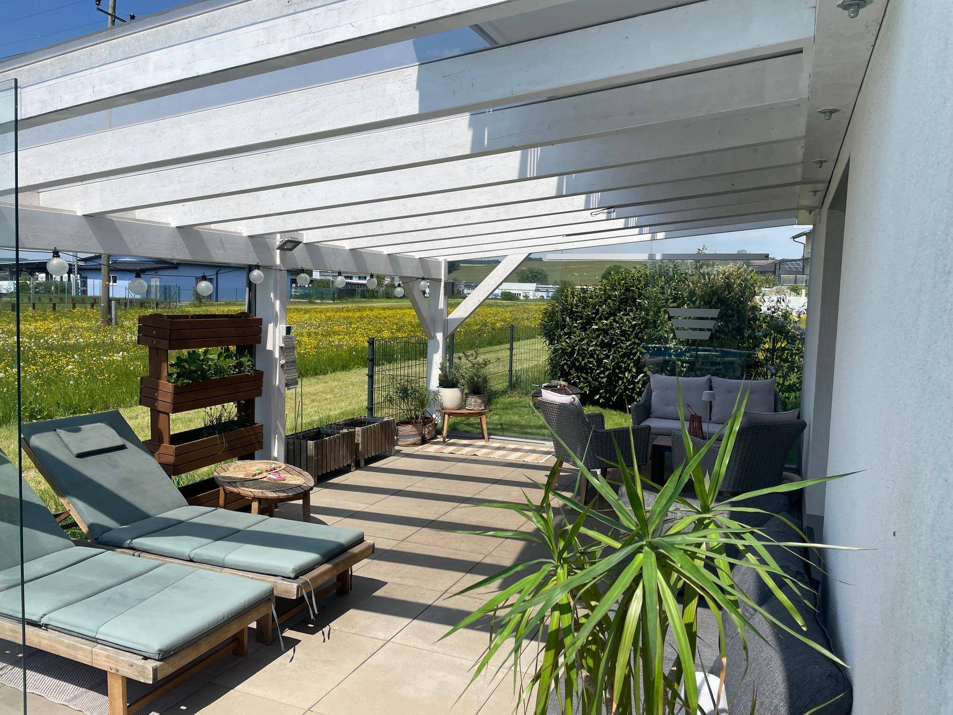 Überdachte Terrasse mit bequemen Lounge-Möbeln und Blick auf die umliegende Natur.