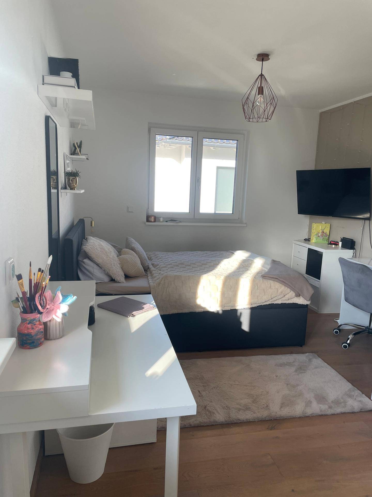 Helles Schlafzimmer mit Einzelbett, Schreibtisch und Holzboden.