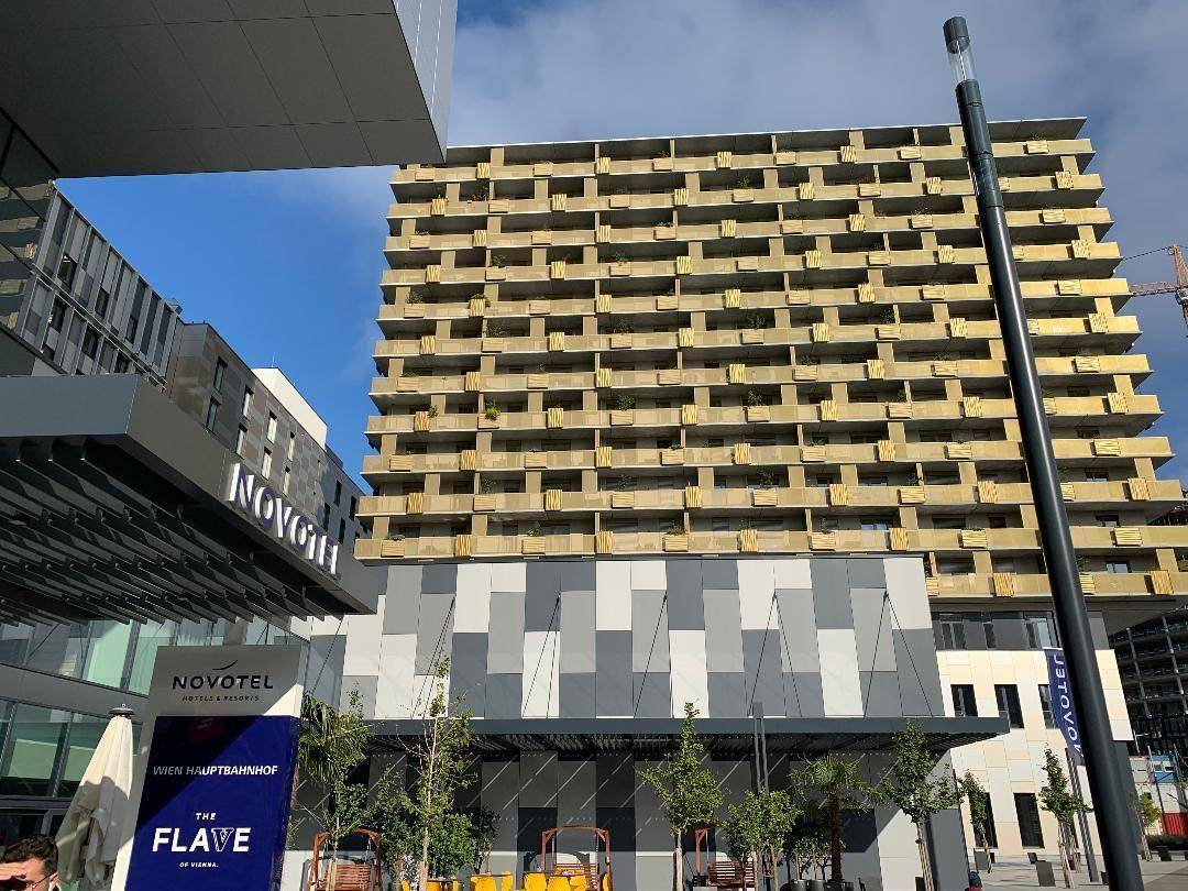 Moderne Gebäudefassade mit vielen Balkonen und angrenzendem Hotelkomplex.